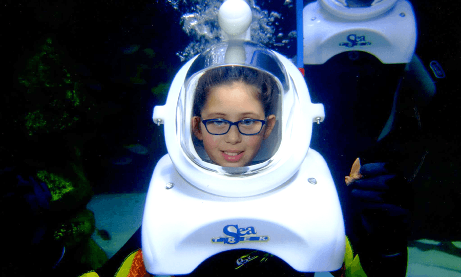 Cute little girl sea trekker with glasses and holding a shark tooth